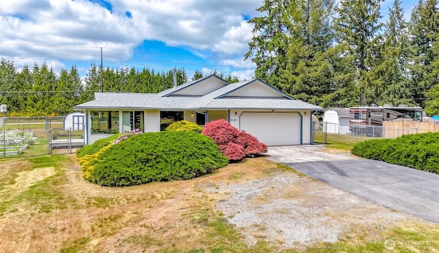 single story home featuring a garage, driveway, and a storage unit
