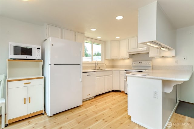 kitchen with white appliances, a sink, light wood-type flooring, a peninsula, and white cabinetry
