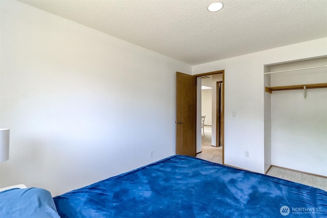 unfurnished bedroom featuring carpet flooring, a closet, a textured ceiling, and baseboards