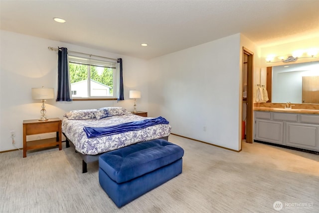 bedroom with light colored carpet, baseboards, a sink, recessed lighting, and connected bathroom