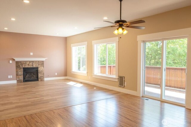 unfurnished living room featuring light wood-style floors, ceiling fan, baseboards, a tile fireplace, and recessed lighting