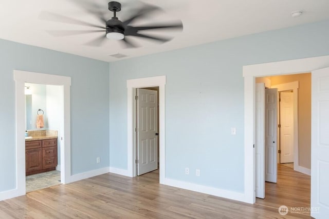 unfurnished bedroom featuring light wood-style floors, baseboards, and ensuite bath