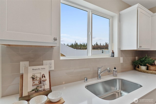 kitchen featuring a sink, decorative backsplash, white cabinetry, and healthy amount of natural light