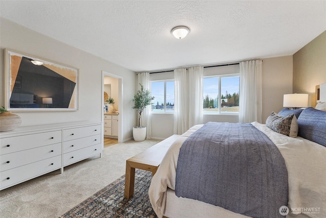 carpeted bedroom featuring a textured ceiling and ensuite bathroom