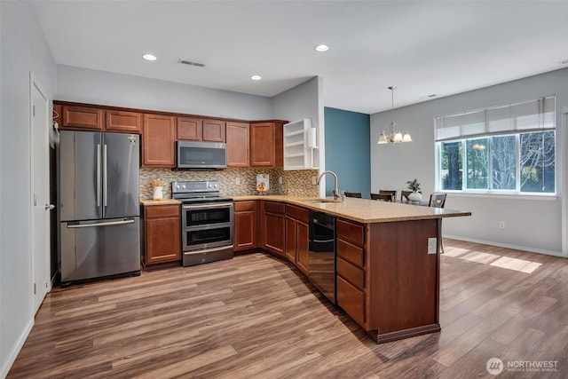 7608 181st Street Ct E, Puyallup, WA 98375 - kitchen with stainless steel appliances, a sink, a peninsula, light wood-style floors, and a chandelier