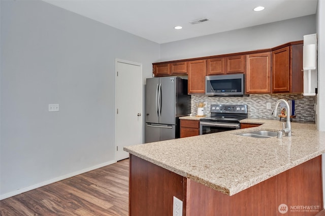7608 181st Street Ct E, Puyallup, WA 98375 - kitchen featuring stainless steel appliances, a sink, backsplash, a peninsula, and dark wood-type flooring