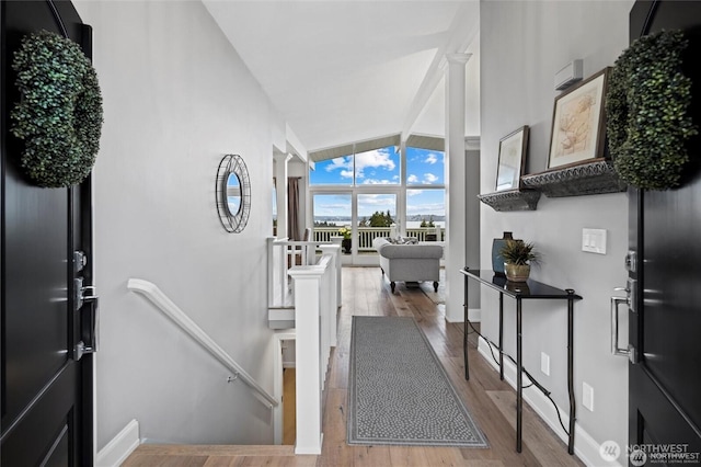 foyer entrance featuring wood finished floors, vaulted ceiling, and baseboards