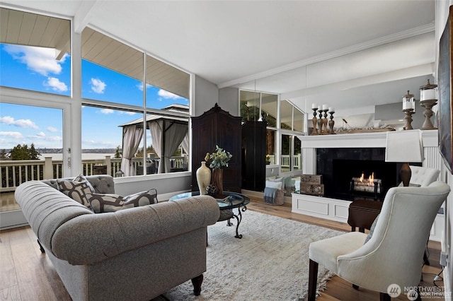 living area featuring wood finished floors, a lit fireplace, and crown molding