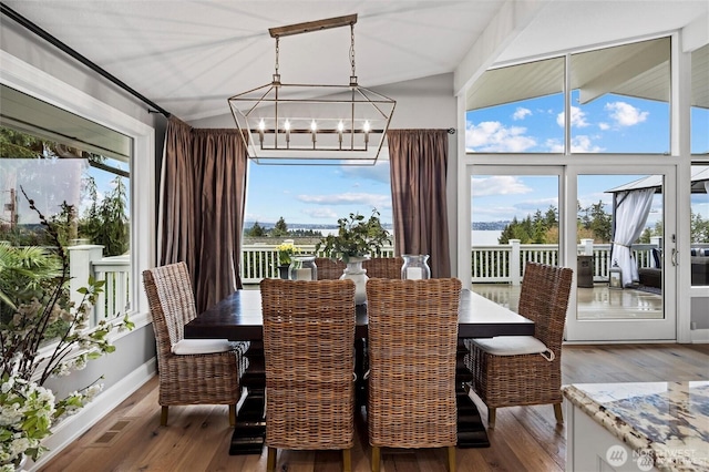 dining space with a chandelier, wood finished floors, and lofted ceiling