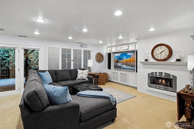 living area with carpet, ornamental molding, a large fireplace, and recessed lighting