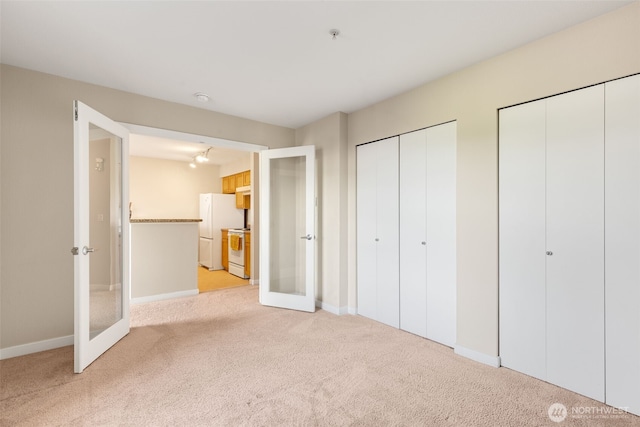 303 23rd Ave S Unit 308, Seattle, WA 98144 - unfurnished bedroom featuring french doors, two closets, freestanding refrigerator, and light colored carpet