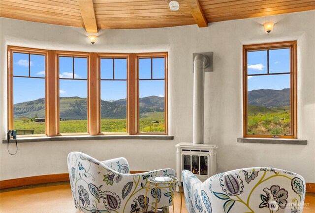 3B Johnny Haase Ln, Winthrop, WA 98862 - sitting room with wooden ceiling with exposed beams, a wood stove, a mountain view, and baseboards
