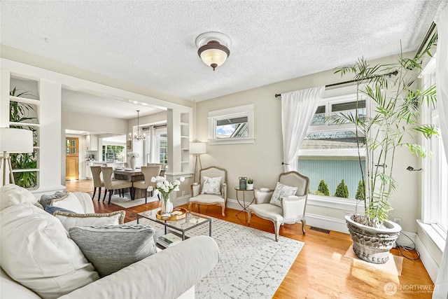 746 N 89th St, Seattle, WA 98103 - living area with plenty of natural light, a textured ceiling, a chandelier, wood finished floors, and baseboards