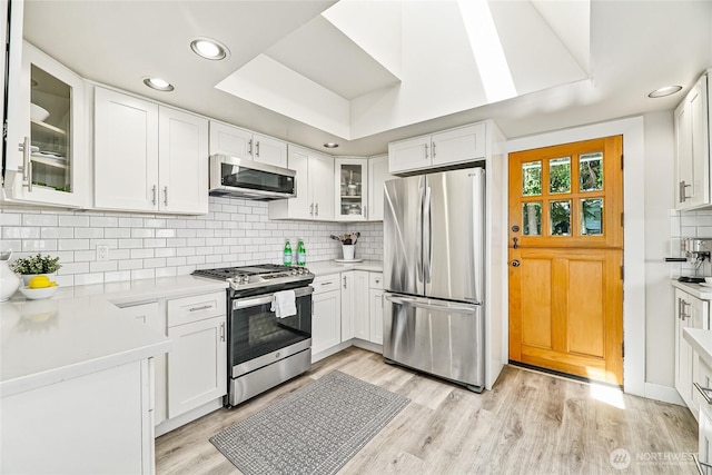 746 N 89th St, Seattle, WA 98103 - kitchen with appliances with stainless steel finishes, light wood finished floors, backsplash, white cabinetry, and recessed lighting