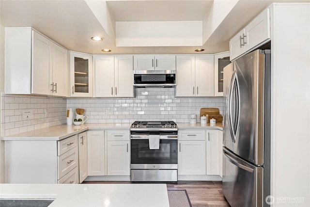 746 N 89th St, Seattle, WA 98103 - kitchen with stainless steel appliances, light countertops, recessed lighting, white cabinetry, and glass insert cabinets