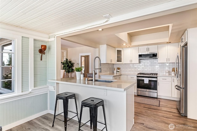 746 N 89th St, Seattle, WA 98103 - kitchen with appliances with stainless steel finishes, a sink, a breakfast bar area, a peninsula, and decorative backsplash