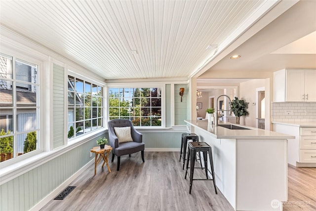 746 N 89th St, Seattle, WA 98103 - kitchen with a sink, a kitchen breakfast bar, white cabinetry, light countertops, and wooden ceiling