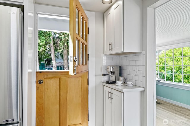 746 N 89th St, Seattle, WA 98103 - bar area featuring freestanding refrigerator, light wood-type flooring, healthy amount of natural light, and backsplash