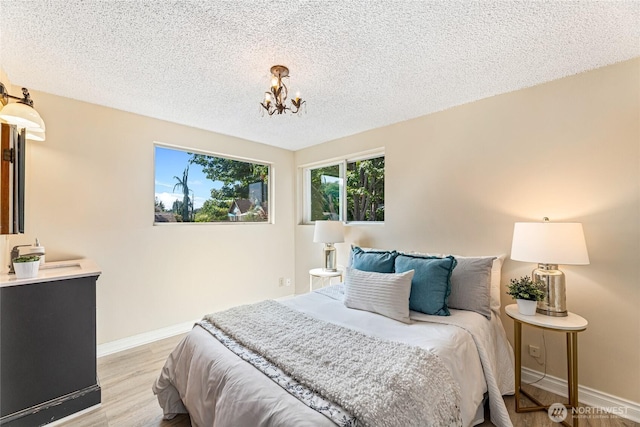 746 N 89th St, Seattle, WA 98103 - bedroom featuring light wood-style flooring, a chandelier, baseboards, and a textured ceiling