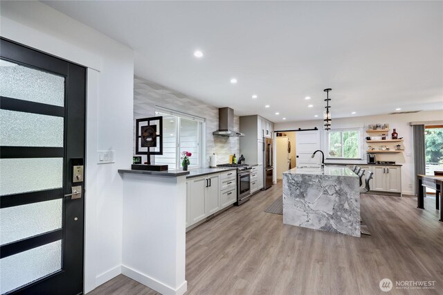 30 Hemlock Ct, Port Townsend, WA 98368 - kitchen with wall chimney range hood, a barn door, high end stainless steel range oven, recessed lighting, and light wood-style floors
