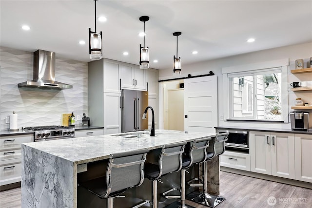 30 Hemlock Ct, Port Townsend, WA 98368 - kitchen with wall chimney range hood, stainless steel appliances, backsplash, a kitchen island with sink, and dark stone counters