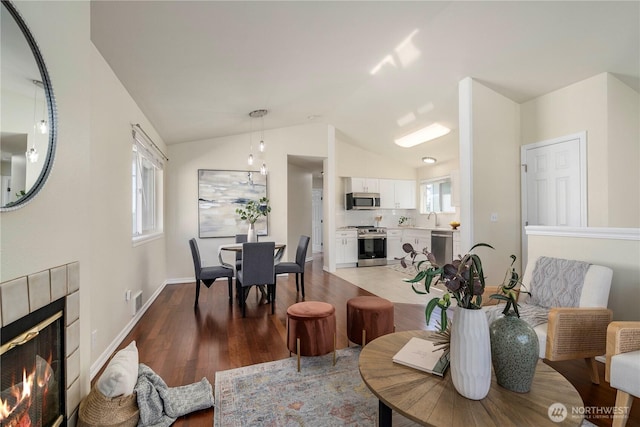 12408 1st Ave SW, Seattle, WA 98146 - dining space featuring vaulted ceiling, light wood finished floors, a tiled fireplace, and baseboards
