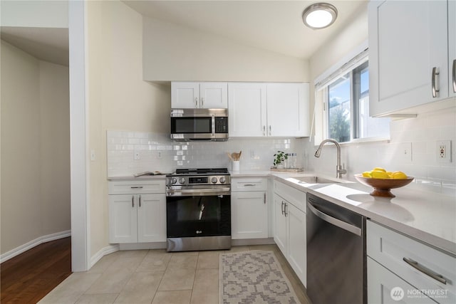 12408 1st Ave SW, Seattle, WA 98146 - kitchen featuring appliances with stainless steel finishes, a sink, white cabinets, lofted ceiling, and backsplash