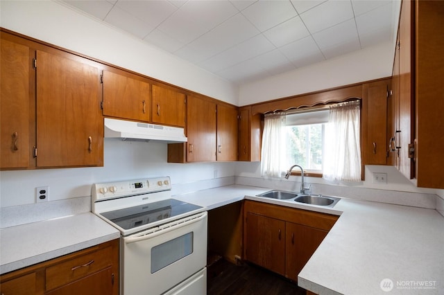 1122 G St, Centralia, WA 98531 - kitchen featuring under cabinet range hood, white range with electric cooktop, a sink, and brown cabinets