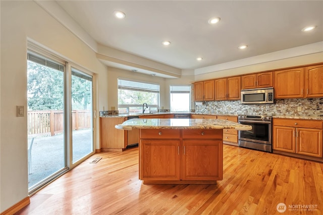 31637 107th Ave SE, Auburn, WA 98092 - kitchen with stainless steel appliances, a kitchen island, light wood-style flooring, a sink, and light stone counters