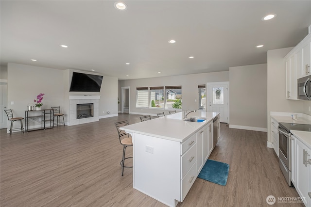 28 S Millbrook, East Wenatchee, WA 98802 - kitchen featuring appliances with stainless steel finishes, a sink, a breakfast bar, light wood-style flooring, and white cabinets