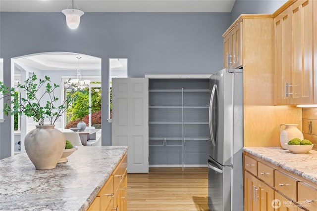 10810 63rd Ave NW, Gig Harbor, WA 98332 - kitchen with freestanding refrigerator, light wood-type flooring, arched walkways, a chandelier, and hanging light fixtures