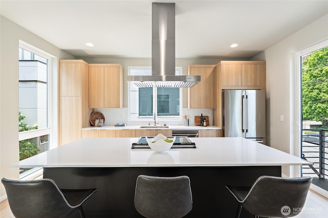 1801 NW 65th St Unit C, Seattle, WA 98117 - kitchen featuring stainless steel appliances, light brown cabinets, island range hood, a breakfast bar area, and recessed lighting