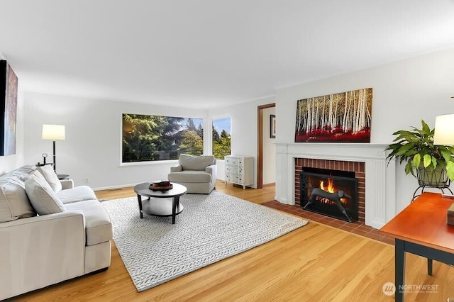 living area with a brick fireplace and wood finished floors
