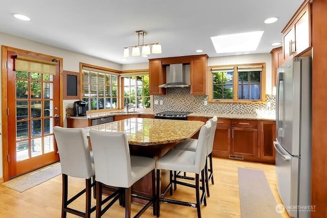 kitchen featuring freestanding refrigerator, wall chimney exhaust hood, a sink, light wood-style flooring, and recessed lighting