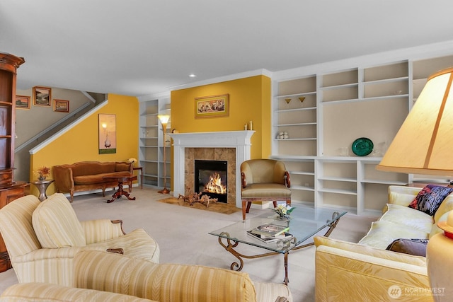 carpeted living area featuring a tiled fireplace, built in features, and stairway