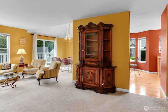 living room featuring a chandelier, light carpet, healthy amount of natural light, and baseboards