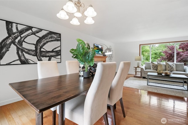 dining space featuring a chandelier, wood finished floors, and baseboards
