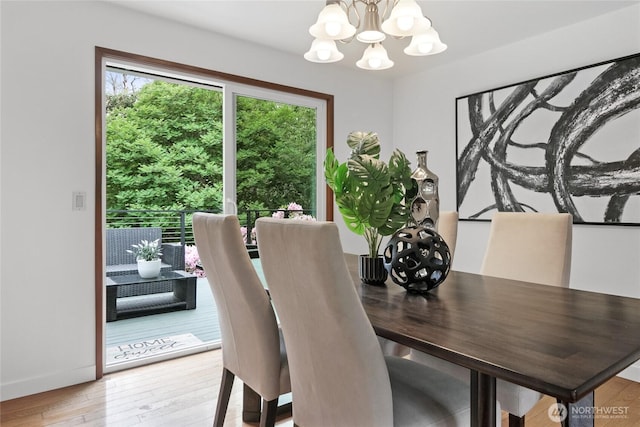 dining area with a chandelier, light wood-style floors, and baseboards