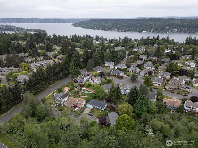 aerial view of property's location with a nearby body of water, a forest, and nearby suburban area