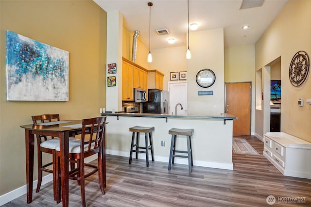 1705 Dock St Unit 520, Tacoma, WA 98402 - kitchen featuring stainless steel appliances, wood finished floors, a breakfast bar, pendant lighting, and a towering ceiling