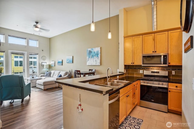 1705 Dock St Unit 520, Tacoma, WA 98402 - kitchen with stainless steel appliances, dark countertops, a sink, a peninsula, and a towering ceiling