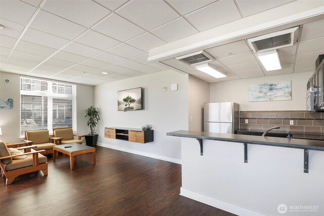 1705 Dock St Unit 520, Tacoma, WA 98402 - kitchen with freestanding refrigerator, dark countertops, stainless steel microwave, a kitchen breakfast bar, and a drop ceiling