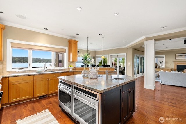 kitchen featuring a sink, decorative columns, a kitchen island, hardwood / wood-style flooring, and recessed lighting