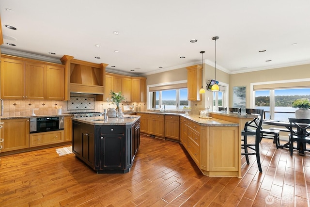 kitchen with custom exhaust hood, a peninsula, a breakfast bar area, light wood-style flooring, and plenty of natural light