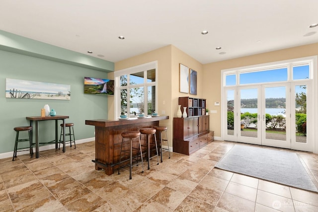 indoor bar featuring baseboards, recessed lighting, and light stone finish flooring