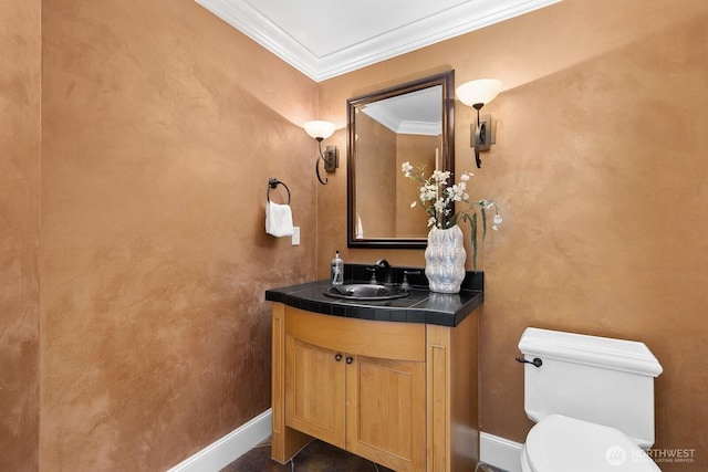 bathroom with toilet, ornamental molding, vanity, and baseboards