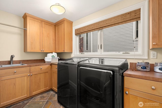 washroom with independent washer and dryer, cabinet space, and dark stone finish flooring