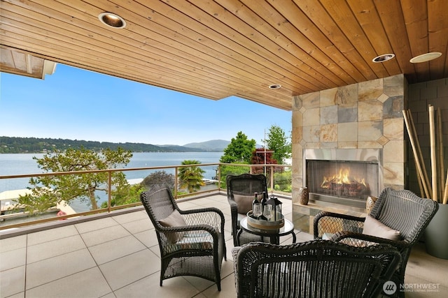 view of patio / terrace featuring a tiled fireplace and a water view