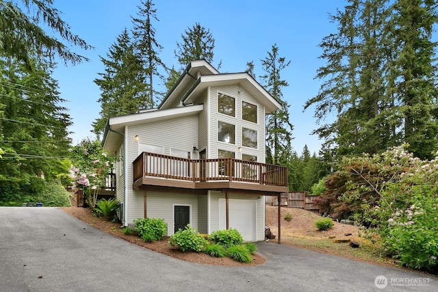 view of front of property featuring asphalt driveway, an attached garage, and a deck