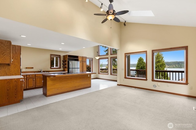 kitchen with freestanding refrigerator, brown cabinets, a sink, plenty of natural light, and high vaulted ceiling